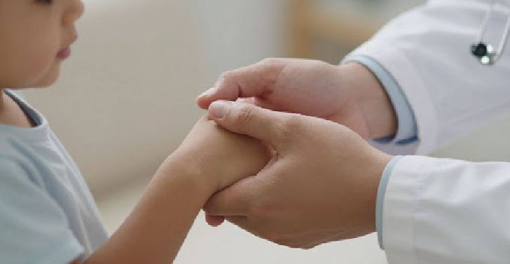 Doctor's hand holding a child's hand, symbolizing care.